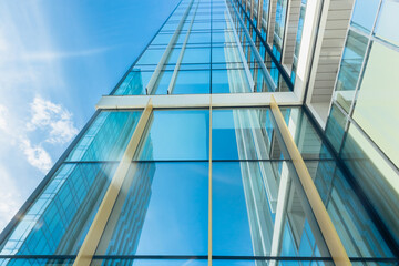 The blue sky is reflected in the windows of a modern office building. Architecture and exterior of...