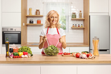 Woman behind a kitchen counter preparing a salad