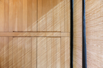 the striped light and shadow on wooden wall from bamboo blind curtain. sun protection curtain of window frame for house decoration.