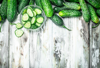 Cucumbers and cucumber slices in a glass bowl.