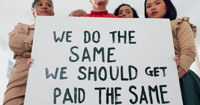 Face, poster and equal pay with a business woman team holding a sign in their office at work for equality. Payment, protest and serious with a female employee group standing to fight for their rights