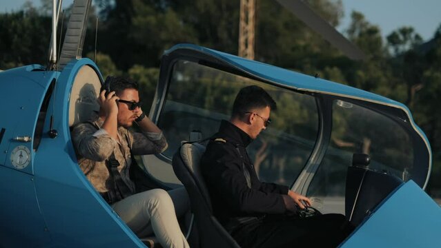 Captain and passenger preparing for flight. The captain and passenger fasten their seat belts. Captain and passenger in a cockpit operating the plane. small private jet. helicopter. 4k uhd 
