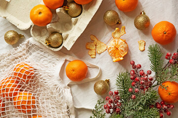 Fototapeta na wymiar Christmas composition with tangerines and gold Christmas toys on a white textural background. Christmas tree with snow and berries. Flatley.