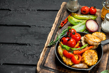 Various grilled vegetables in a pan with spices on a wooden Board.