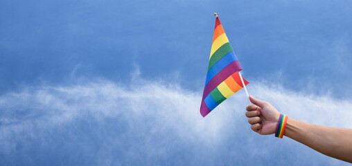 rainbow flag and rainbow wristband, LGBT symbol, holding in hand with copy space