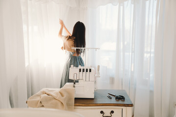 The workplace of a seamstress who sews curtains at home. The girl closes the curtains.