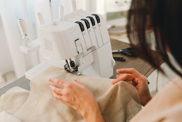 Close-up of a sewing machine and the hands of a seamstress who sews curtains.