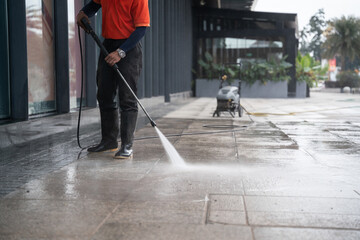 cleaning staff hoses a portable car for washing the concrete floor with high-pressure water jets. - obrazy, fototapety, plakaty