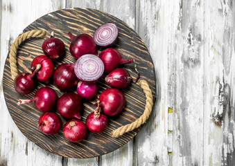 Whole and cut red onions on tray.