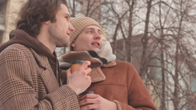 Slowmo Of Happy Caucasian Gay Couple Spending Time With Each Other Having Date Outdoors In Winter, Drinking Coffee From Takeaway Cups And Exploring City