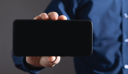 Male hand holding a smartphone with blank screen.