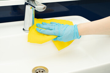 hand with a rag washes the sink in the bathroom