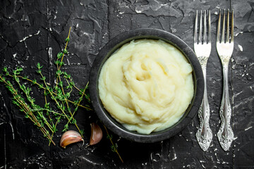 Mashed potatoes in a bowl with garlic and thyme.