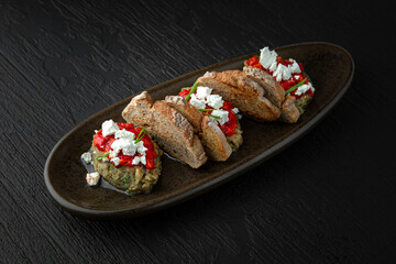 Eggplant caviar with baked pepper in a ceramic plate on a dark textured background. Restaurant menu Isolated on black
