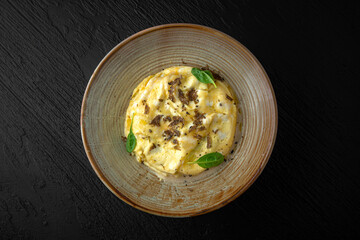 Polenta with mushroom julienne and truffle in a ceramic plate on a dark textured background. Restaurant menu Isolated on black