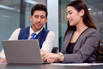 Obraz premium Manager and employee working at desk using laptop in office.