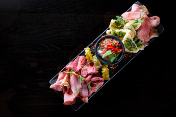 plate with meat, ham, backon, prosciutto on Dark grey black background