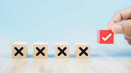 Hand choose check mark on cube wooden toy block with cross symbol for true or false changing mindset or way of adapting to change leader and transform quiz answer and poll concept.