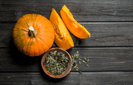 Pumpkin seeds in a bowl and pieces of ripe pumpkin.