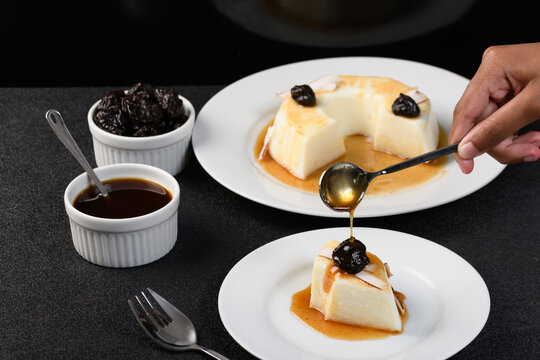  slice of coconut manjar on a white plate, plum syrup falling over the manjar 
