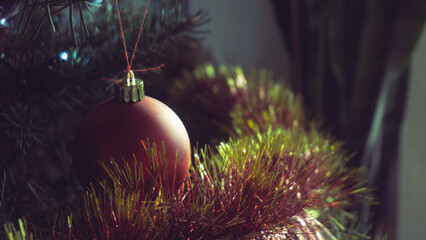 Christmas ball hung on the Christmas tree with tinsel garland