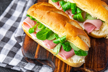 sandwich ham french milk bun, cheese, lettuce green leaves bio product fresh healthy meal food snack on the table copy space food background rustic top view