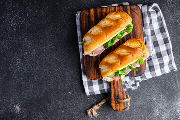 sandwich ham french milk bun, cheese, lettuce green leaves bio product fresh healthy meal food snack on the table copy space food background rustic top view