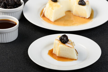 slice coconut blancmange with prune syrup on a white plate
