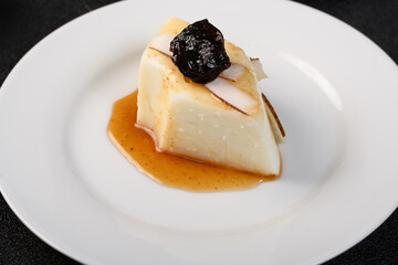 slice coconut blancmange with prune syrup on a white plate
