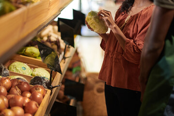 Cropped image of customer buying cabbage in supermarket