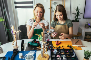 Mother and daughter accessories designers making handmade jewelry in studio workshop. Fashion, creativity and handmade concept.