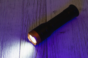 LED flashlight on wood table - obrazy, fototapety, plakaty