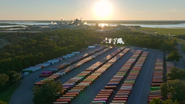 Large cargo container yard with many freight containers and big factory manufactory structure.