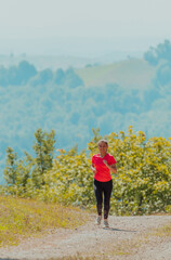 Young happy woman enjoying in a healthy lifestyle while jogging on a country road through the beautiful sunny forest, exercise and fitness concept