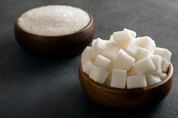 Cube sugar and granulated sugar on dark background
