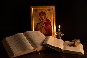 Icona di Maria con Gesù bambino illuminata da un piccolo lume con davanti aperte due bibbie