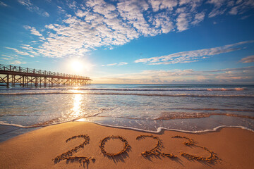 New Year 2023 beach sunrise. Text 2023 in sea sand, nature ocean landscape