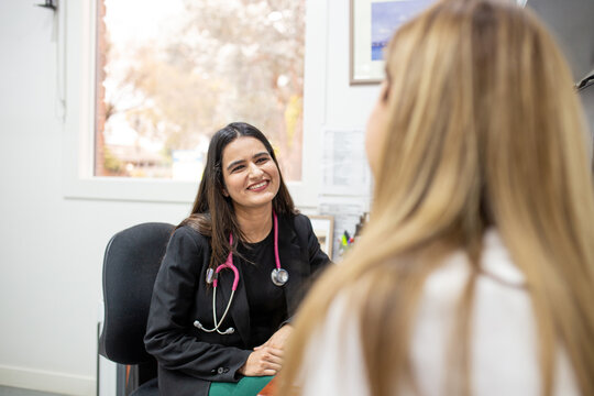 Female doctor smiles as she listens to her female patient