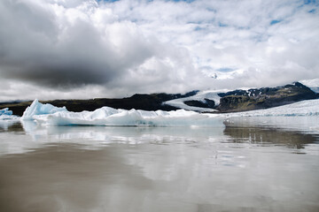 Many icebergs and ice floes in the glacial lagoon Fjallsárlón in iceland, which has broken away from the glacier tongue Fjallsjökull. With a view of Hvannadalshnúkur in the background.