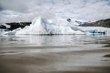 Many icebergs and ice floes in the glacial lagoon Fjallsárlón in iceland, which has broken away from the glacier tongue Fjallsjökull. With a view of Hvannadalshnúkur in the background.