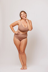 Fototapeta premium Confident caucasian woman plus size, wearing underwear and smiling, against white background, body positivity concept