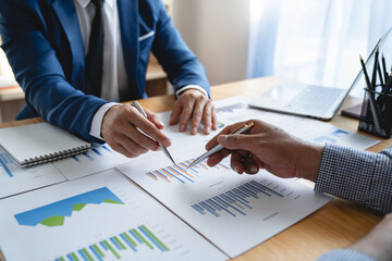 Young Asian businessman analyzing and discussing and brainstorming chart data. financial report graph in the office financial advisor and accounting concept.