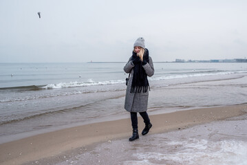 Stylish girl walks along the sea or ocean coast on a cool winter day. Travel concept. Walk on the sea or ocean. Amazing scenic outdoor view