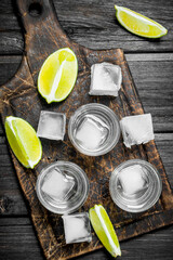 Fototapeta na wymiar Vodka with ice on a cutting Board with slices of lime.