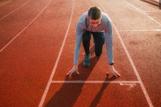 Young athlete in position on the starting blocks on a track. Runner ready for the start, symbol of preparation and success