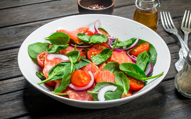 Fish salad. Salad with slices of salmon, tomatoes and spinach with lime juice.