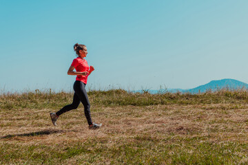 Young happy woman enjoying in a healthy lifestyle while jogging on a country road through the beautiful sunny forest, exercise and fitness concept