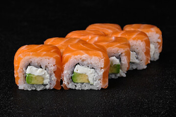 salmon sushi roll on black background
