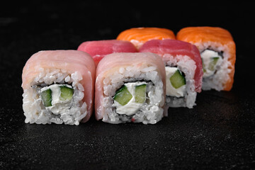 Salmon; Tuna; Amberjack fish sushi roll on black concrete background