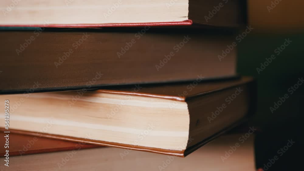 Poster close-up of a stack of colorful old hardcover books in rays of sunlight. camera movement from the bo